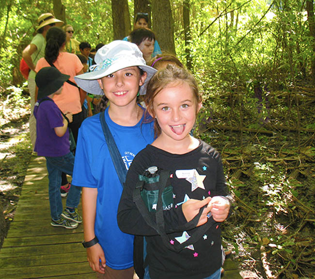 Two friends posing for a picture in the woods at camp