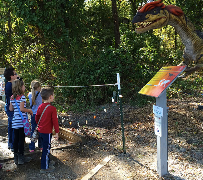 Children staring at a dinosaur that spits water